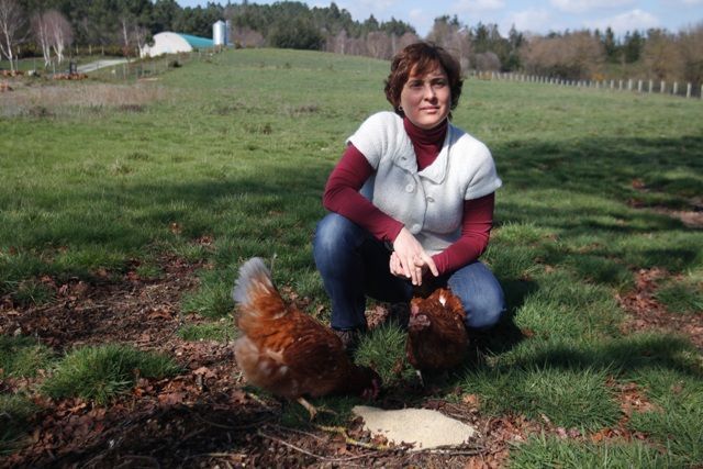 Nuria Varela-Portas con dúas das súas galiñas alimentándose de penso, en Pazo de Vilane.

