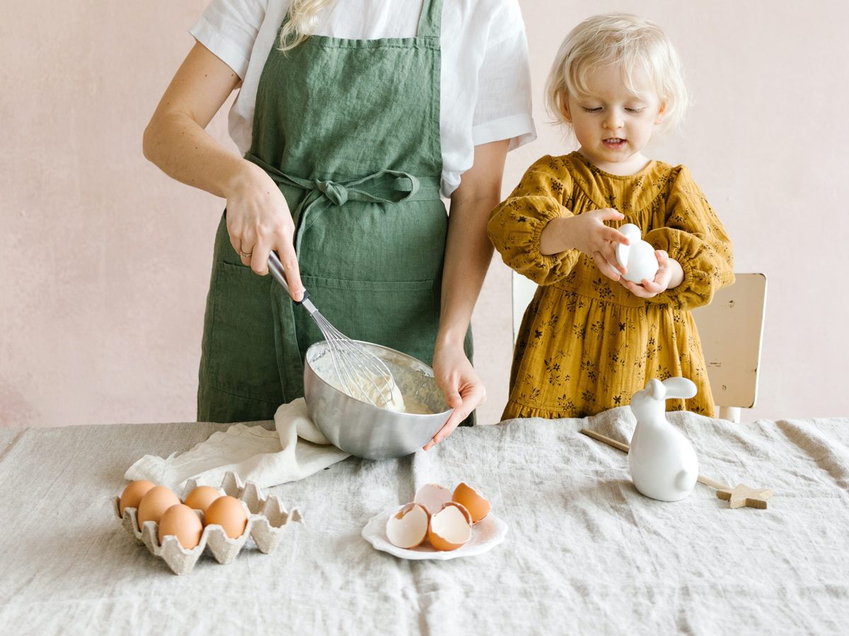Niña cocinando huevos con su madre